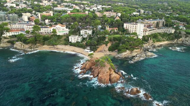 Aerial drone footage of Platja d&rsquo;Aro on the Costa Brava in Catalonia, Spain. Elevated view shows the Mediterranean coastline, sandy beach, turquoise water, bay, and rocky coastal features alongside th