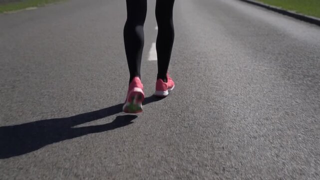 running shoes and leg of women on a aspalt road with marking line 