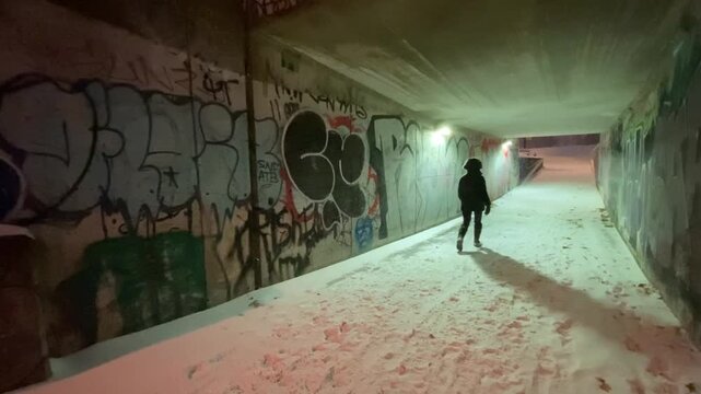 a woman walks through a tunnel during snowfall