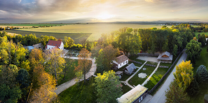 Landscape panorama aerial of village Pac - Archeopark at sunset with forest and field