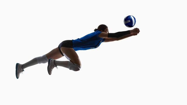 Airborne volleyball player diving fully extended toward incoming ball. Concept of defensive skills, libero training, reaction development, technique instruction and professional movement analysis.