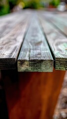 Close Up View Of Weathered Wooden Table Surface With Textured Grain And Outdoor Blurred Greenery Background