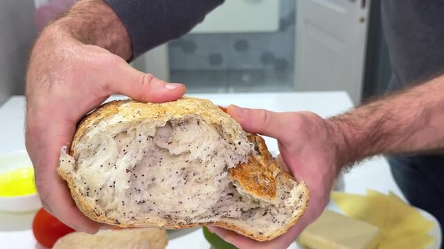 Close up of baker hands breaking homemade bread