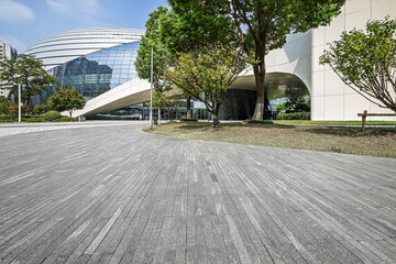 Empty square floor and modern city architecture with green trees.