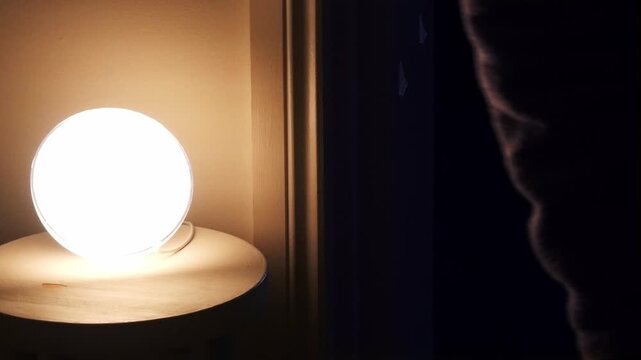 Close up of a person entering room lamp with motion sensor provides automated lighting when activated. Improves energy efficiency security. Contemporary design.. Warm light illuminates textured