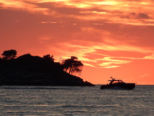 silhouette of small island with pine trees in Adriatic sea in Rovinj, with burning sky at sunset in the background