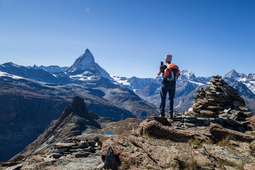 hiker on top of the mountain at gornergrad valais switzerland photographing mount matterhorn
