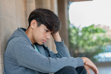 A quiet, melancholic moment. A middle school student, wearing a grey hooded sweatshirt, sits alone with a sad, introspective expression. Capturing feelings of solitude and youthful contemplation.