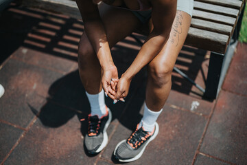 Relaxing on a wooden bench, a young woman in active wear takes a break outdoors. The image highlights fitness attire and a serene moment during a workout or casual outdoor activity.