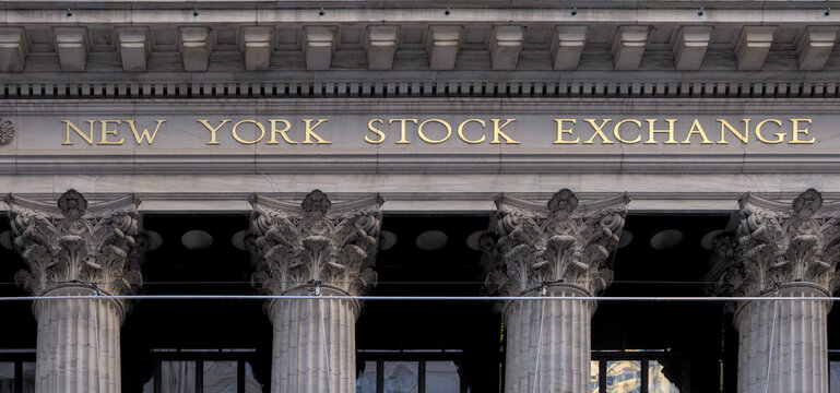 new york stock exchange building with american flags waving in the breeze in front (famous neoclassical finance economy landmark) securities financial trade trading floor wall street new york city usa