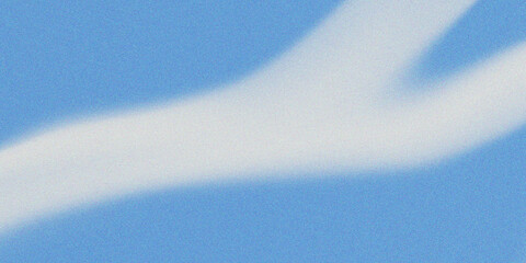 A white contrail stretches across a clear blue sky with a wavy trail