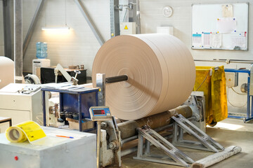 A large roll of freshly produced paper roll, at a paper mill, being prepared for shipment