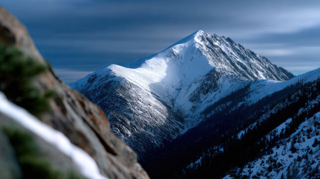 A striking snow-covered mountain peak rises majestically against a dramatic cloudy sky, embodying nature's beauty and the rugged wilderness with a serene and powerful presence. - Powered by Adobe