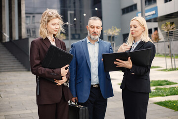 Business people standing and talk to each other in front of modern office