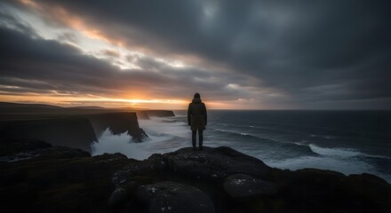 Solitary figure standing on cliff edge overlooking stormy ocean at dramatic sunset