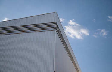 Aluminium White Corrugated Steel Wall of Geometric Warehouse Industrial Factory Building against Blue Sky Background in Modern and Minimal Design, Low angle and Perspective Side view