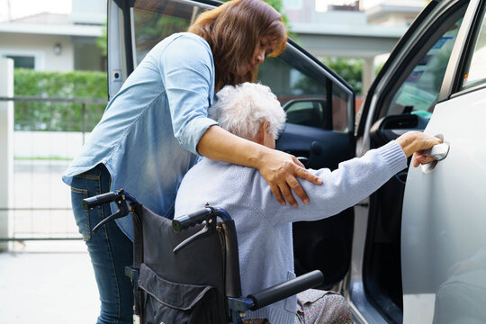 Caregiver help Asian elderly woman disability patient use wheelchair to get in car.
