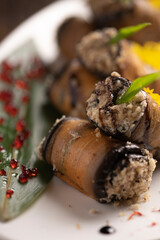 Baked eggplant rolls on a white plate .