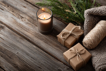 Rustic holiday arrangement featuring wooden textures, a lit candle, wrapped gifts, and twine accents. Warm, natural colors convey a handcrafted, festive vibe perfect for seasonal stock photography or