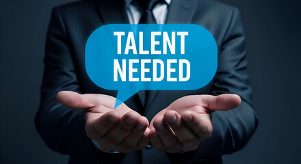 Businessman presenting glowing blue speech bubble with the words talent needed held above open hands against a dark professional background symbolizing recruitment needs