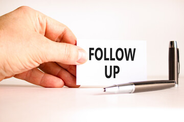 Follow up symbol. Concept word Follow up on beautiful white card. Beautiful black pen. Beautiful white paper background. Businessman's hand. Business follow up concept. Copy space.