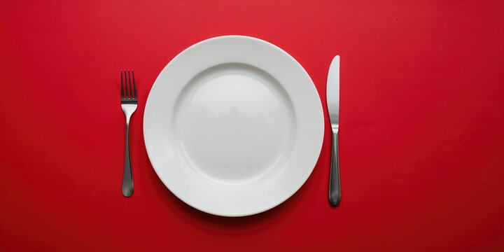 Minimalist table setting with a white plate on a red background, suitable for UI background design