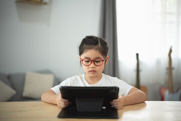 Young Girl Focused on Tablet in Modern Room with Natural Light