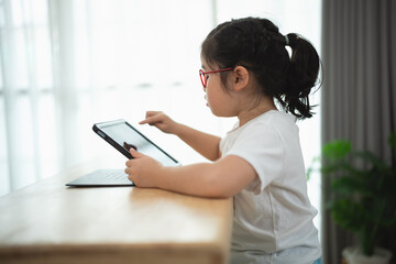 Young Girl Engaged with Tablet in Bright Room by Window
