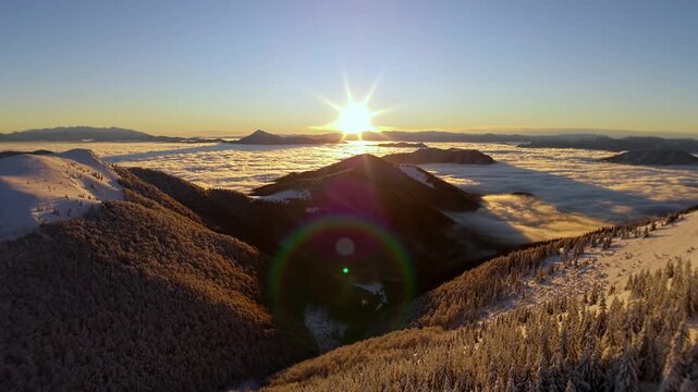 Aerial sunrise pullback over winter mountains above sea of clouds inversion in Carpathians