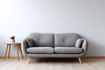 Gray sofa with wooden table and plant against a light wall.