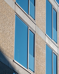 Obraz premium Modern building facade with large windows reflecting clear blue sky during daylight