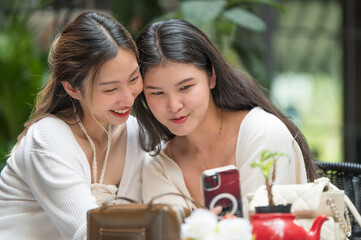 Two close friends smiling and looking at a smartphone together.