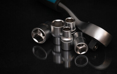 Metal ratchet wrench with a socket head lying on a dark surface. Tool concept for repair, mechanics, maintenance, engineering, and professional workshop work.