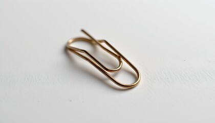 A single gold paperclip resting on a white surface.