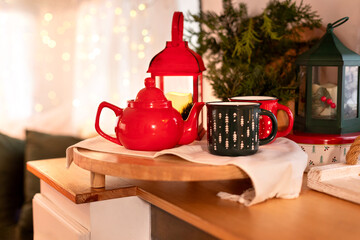A wooden tray with red teapot and holiday cups of hot beverage in kitchen rv trailer home indoors. Template. Tea time. Christmas festive cozy decoration on table top at home.	
