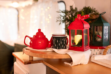 A wooden tray with red teapot and holiday cups of hot beverage in kitchen rv trailer home indoors. Template. Tea time. Christmas festive cozy decoration on table top at home.	
