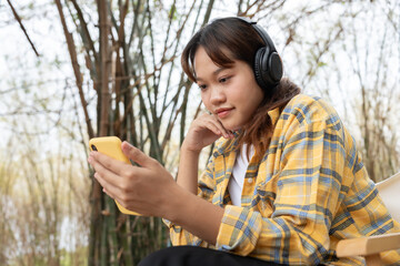Joyful young Asian women sitting in the garden and enjoy life on holiday, having fun, listening to music, raising his arm, dancing to favorite song, enjoying cool soundtrack, happy life, recreation
