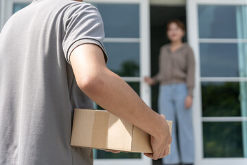 Happy smiling woman receives boxes parcel from courier in front house. Delivery man send deliver...