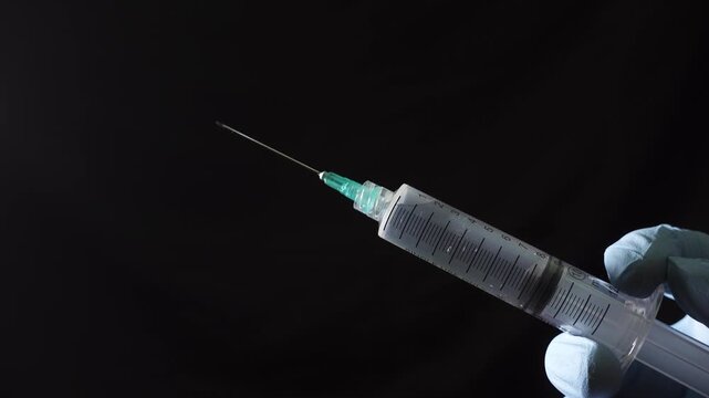Hands of a healthcare provider removing the cap from a syringe needle as part of the preparation for drug administration