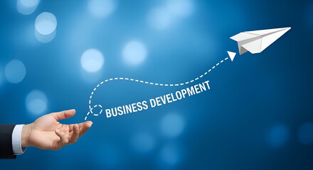 Businessman launches paper airplane symbolizing business development growth trajectory against a vibrant blue bokeh background representing future success and opportunity