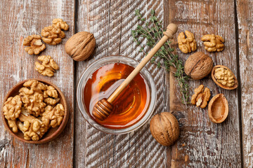 Honey in bowl, walnuts and thyme on wooden table, flat lay