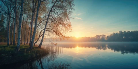 Fototapete Reflection Morning sunrise illuminates birch trees reflected in a tranquil blue lake, highlighting seasonal change  © TheWaterMeloonProjec
