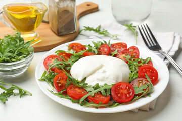 Delicious burrata cheese with arugula and tomatoes on light table, closeup