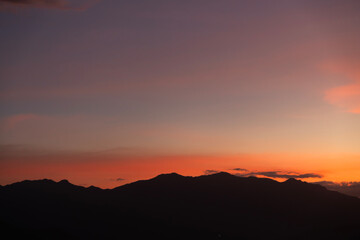 Bright sunset over the silhouette mountains at evening time.