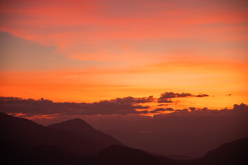 Bright sunset over the silhouette mountains at evening time.