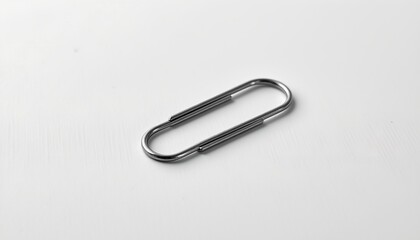 A silver paperclip resting on a surface with a soft gradient of gray hues, transitioning to white at the bottom.