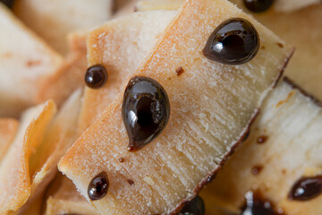 Macro shot of toasted coconut pieces with glossy chocolate drops.
