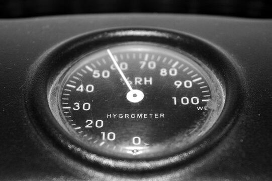 Close-up monochrome (black and white) shot of an analog Hygrometer dial showing relative humidity (RH). Concept for vintage technology, precise measurement, control panel, and industrial gauge.