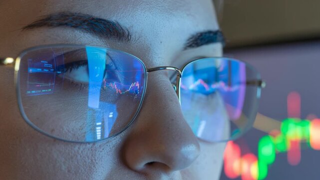 Close up of person wearing glasses reflecting stock market charts and economic data, focusing on finance, business investment, growth analysis, and digital trading graphs in modern office environment