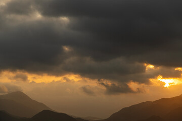 Bright sunset over the silhouette mountains at evening time.